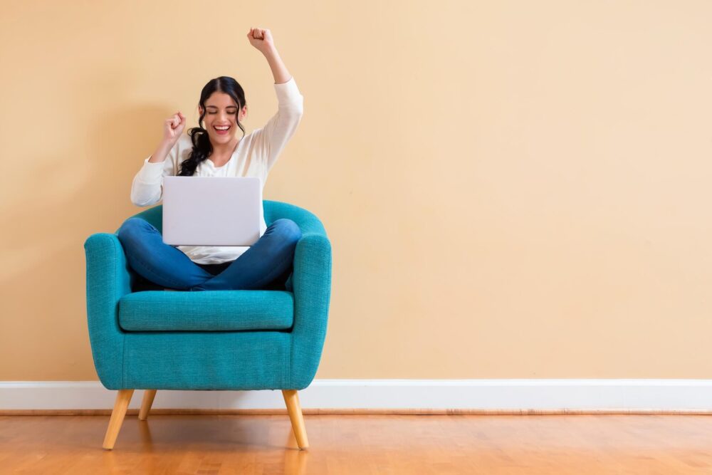 A girl with her fist up in front of a laptop 