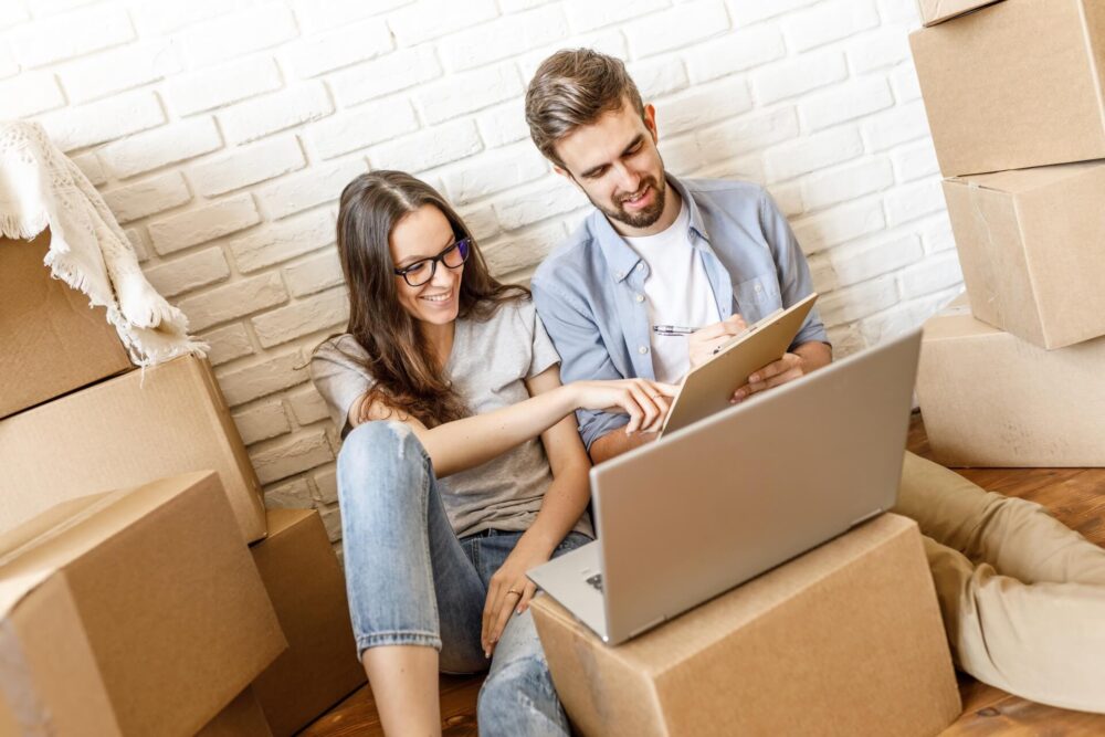 A man and woman smiling while organizing a cross-country relocation 