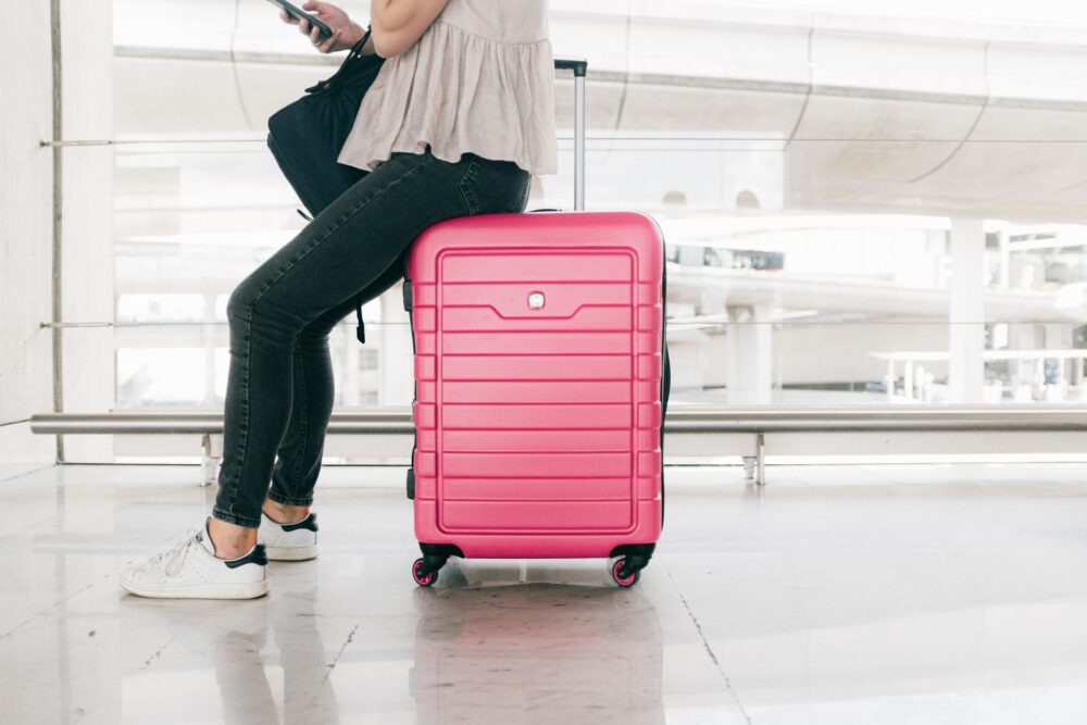 A person sitting on a pink suitcase 