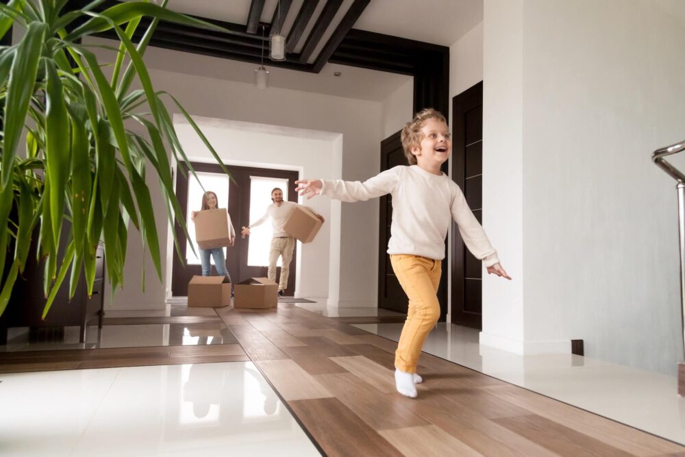 A child running down the hallway with parents in the background