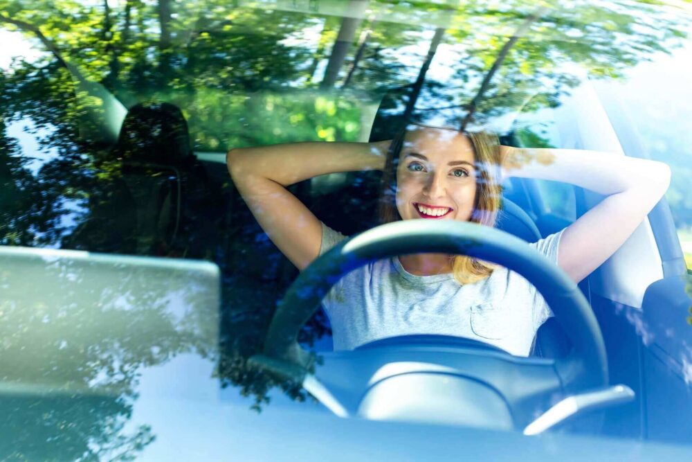 A woman sitting happily in her car