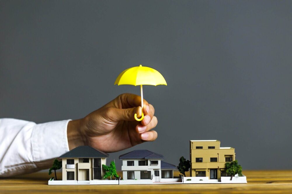 Man holding a tiny umbrella above models of buildings