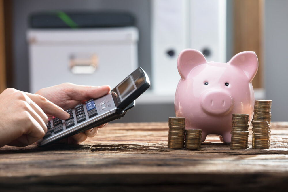 A calculator, a piggybank, and money on the table