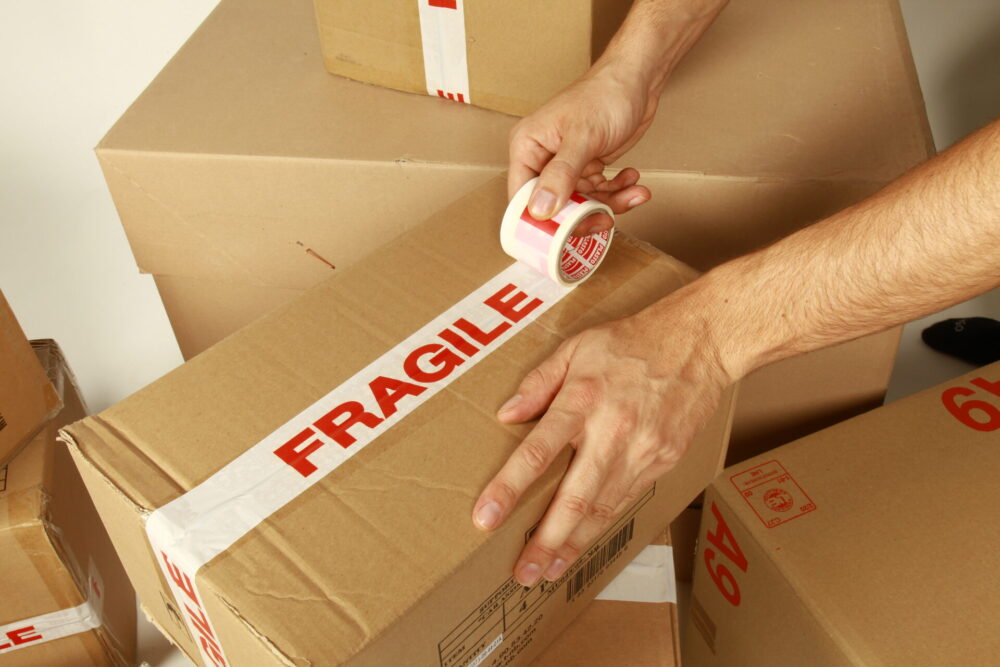 Taping a fragile label on a box before long-distance moving 