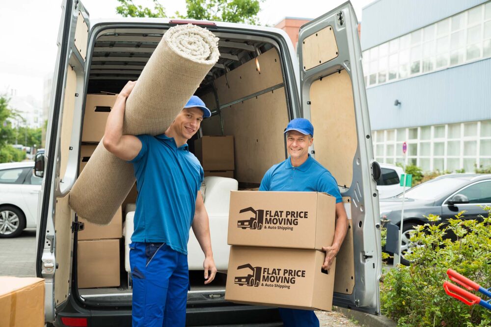 Two long-distance movers holding boxes and a carpet