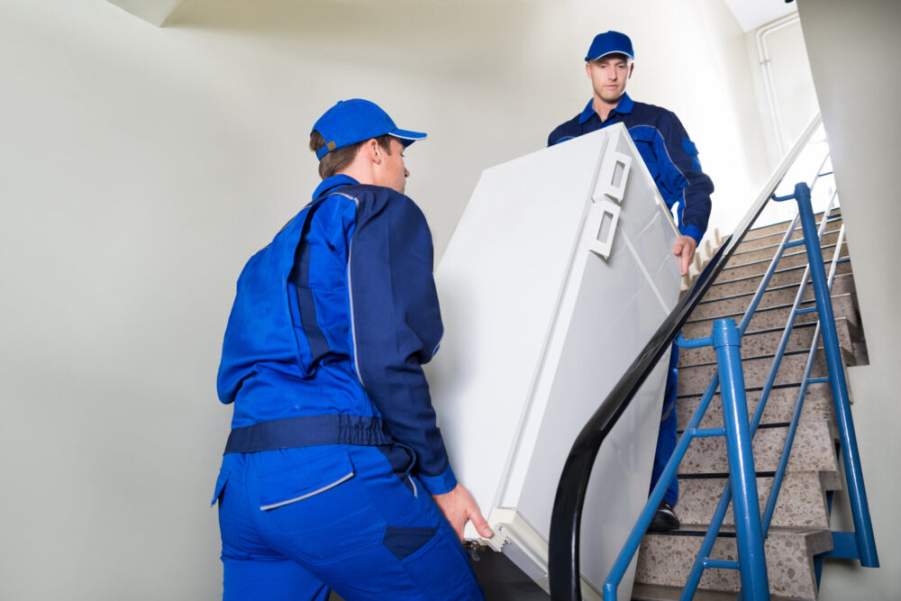 Movers carrying a fridge up the stairs 