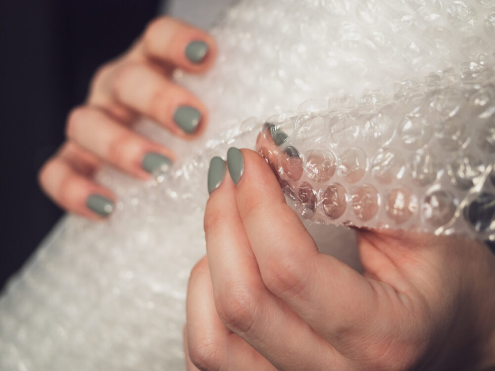 Woman holding a roll of bubble wrap before cross-country moving