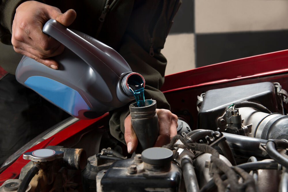 A person refilling a car with antifreeze