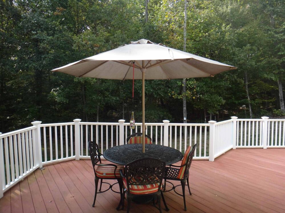 Porch with white fence, table, chairs, and a parasol 