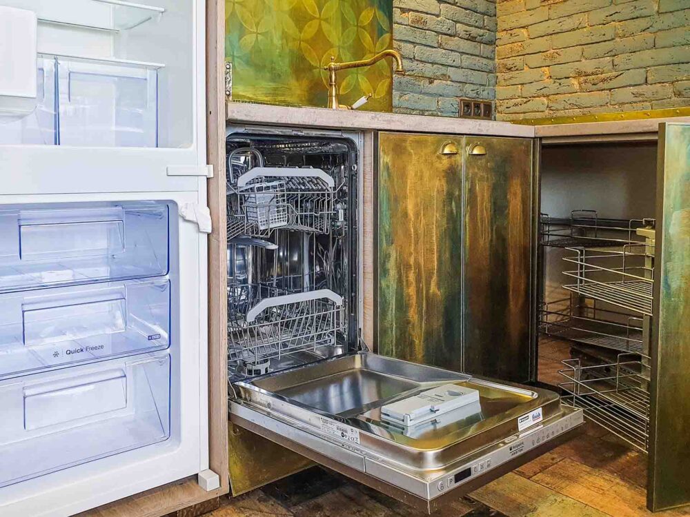 A kitchen with an empty dishwasher and fridge