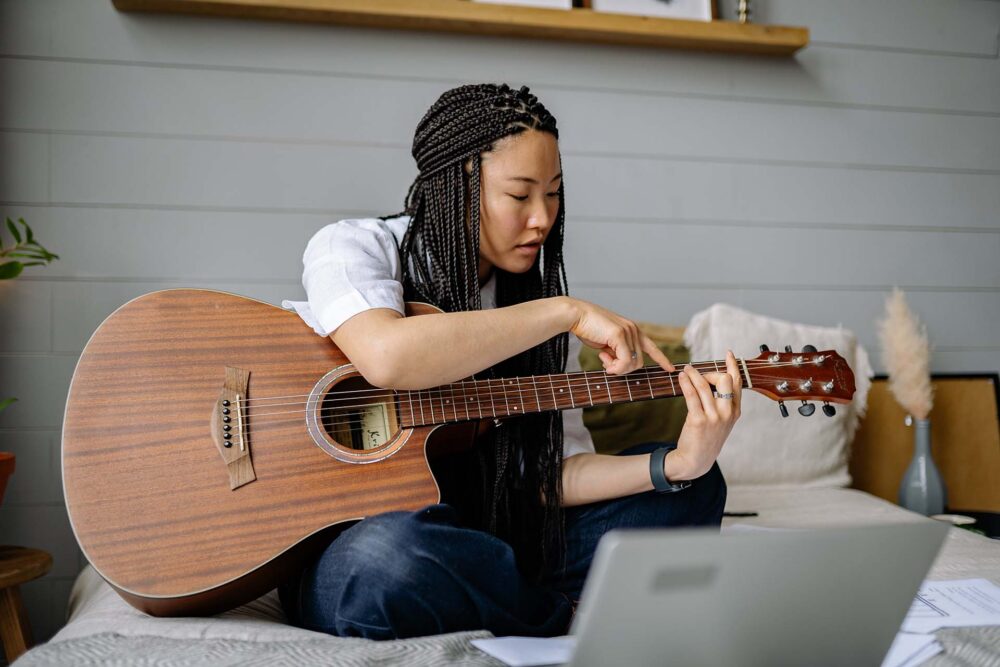 A woman touching the strings of her guitar