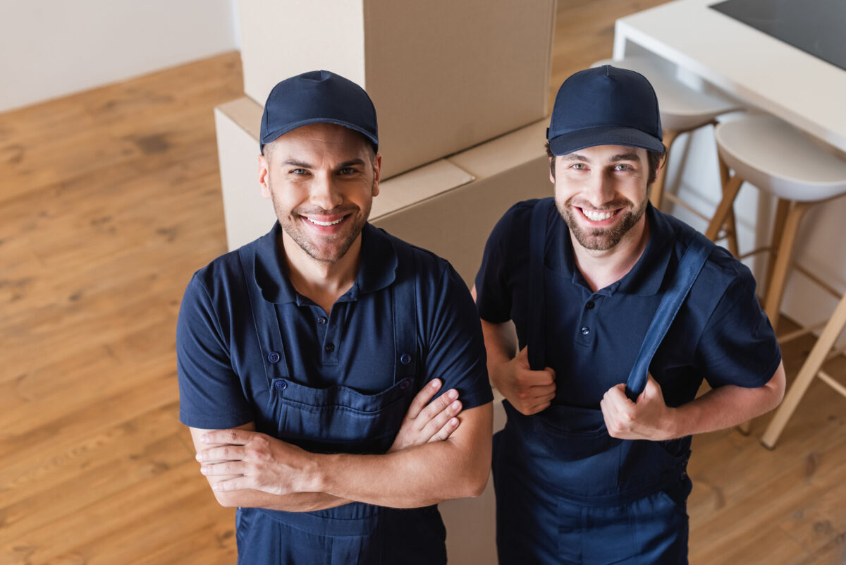Long-distance movers smiling and standing in front of boxes