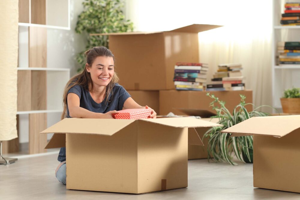 Happy girl filling boxes for cross-country moving