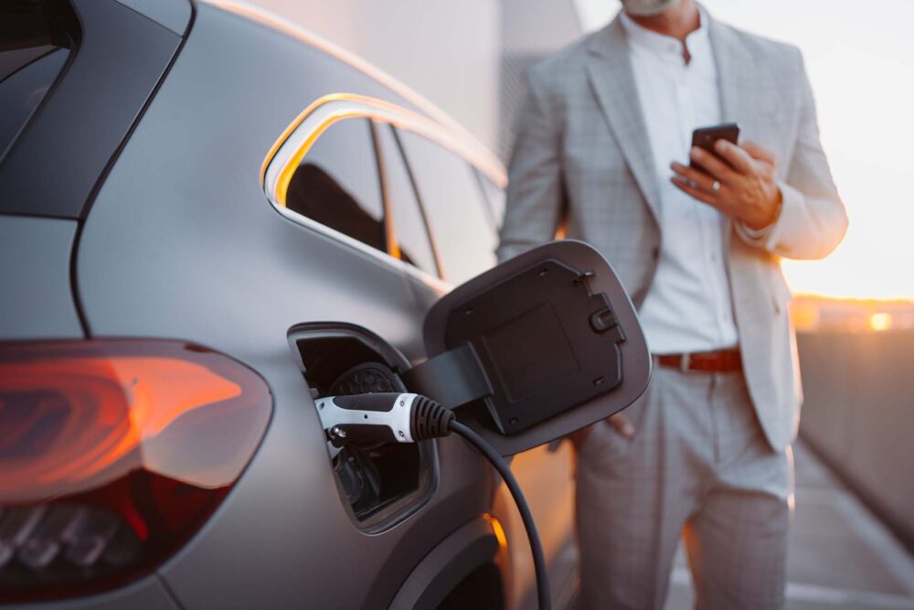  A man in a suit standing beside an electric car