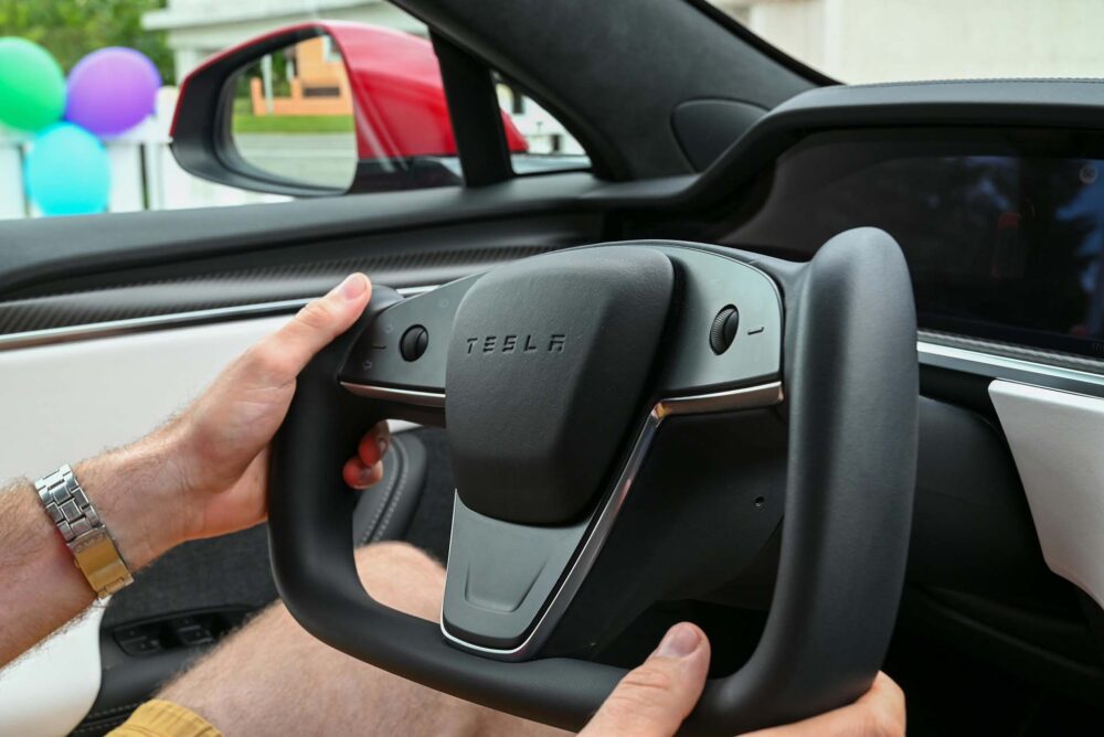  Man holding a Tesla steering wheel