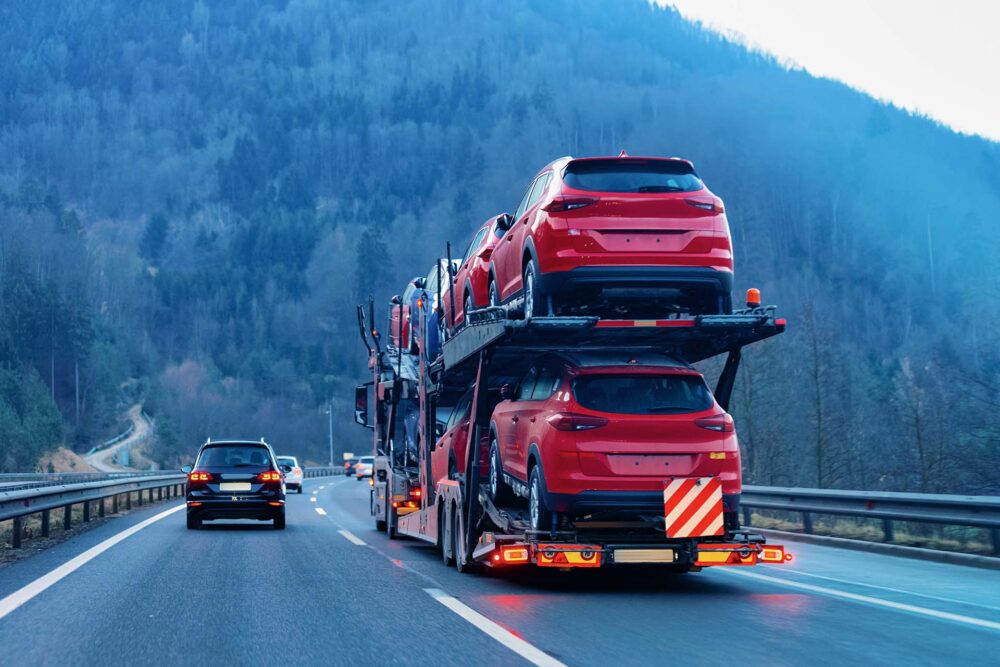 An open carrier transporting red cars 