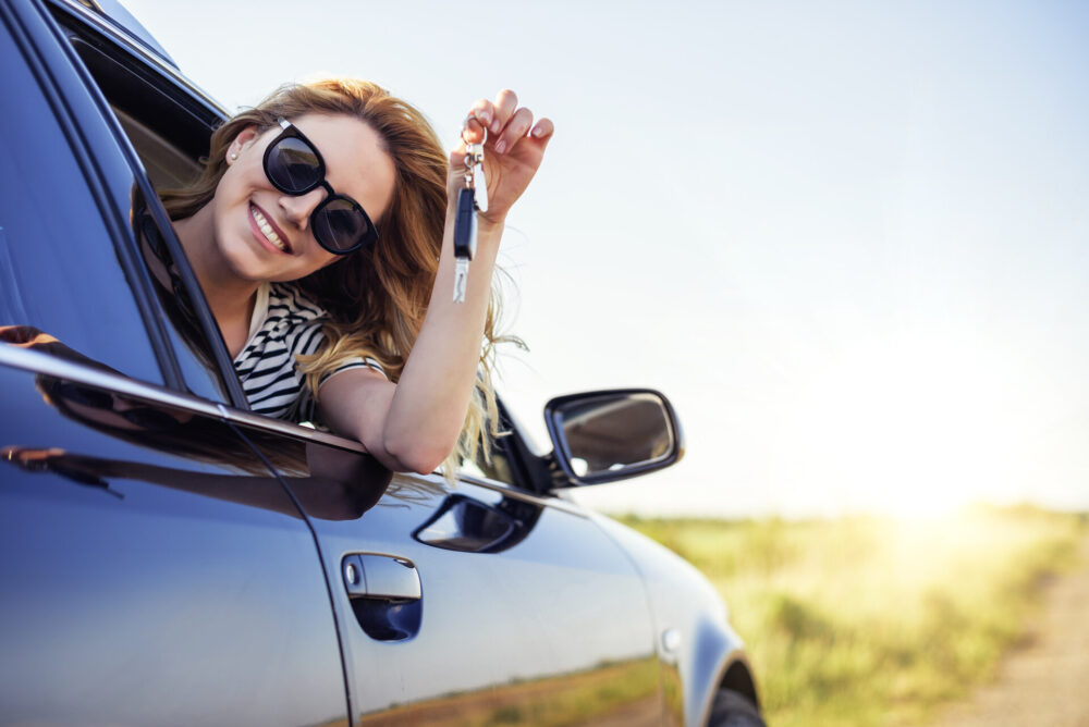 A woman sitting in a car and holding car keys