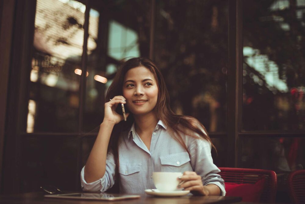 Woman Using Mobile Phone in Cafe